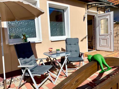 a patio with a table and chairs and a green creature at Ferienwohnung in der Seestraße in Sassnitz
