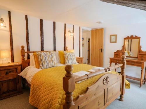 a bedroom with a large bed with a yellow comforter at Bridge Cottage in Bridport