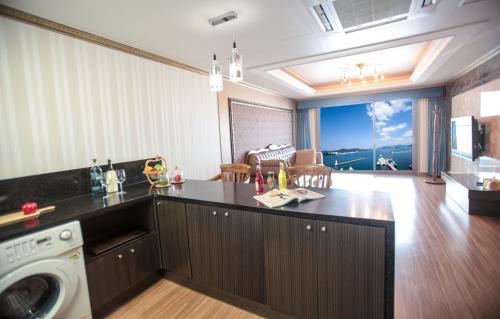 a kitchen with a washing machine and a living room at Tongyeong Bay Condo Hotel in Tongyeong