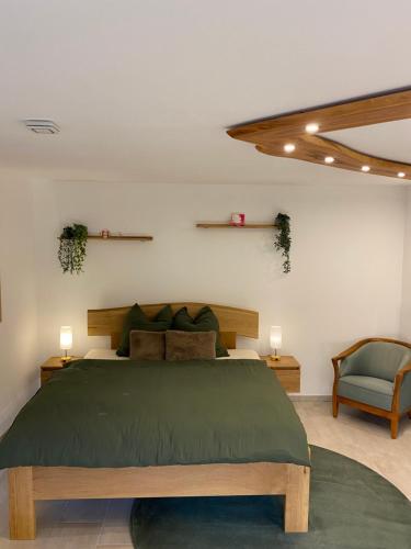 a bedroom with a large green bed and two chairs at Stübchen Nr 37 in Inzigkofen