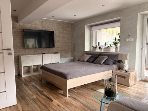 a bedroom with a bed and a tv on a brick wall at Breńskie Tarasy in Brenna