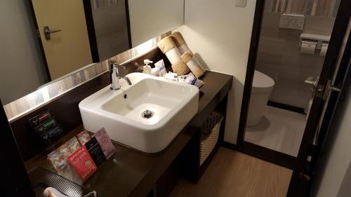 a bathroom with a white sink and a toilet at ホテルピュアゲート in Isesaki