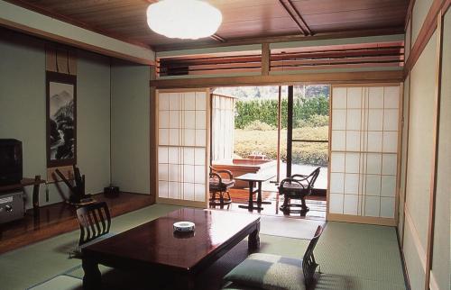 Una sala de estar con una mesa y sillas y una ventana. en Oyado Sansui, en Achi