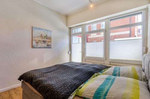a bedroom with a bed and two windows at Alte Teestube in Norderney
