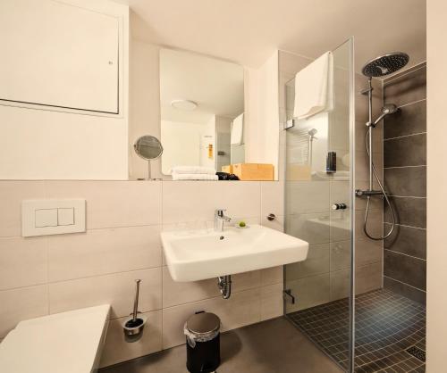 a white bathroom with a sink and a shower at ADAPT APARTMENT HOTEL Siegen in Siegen
