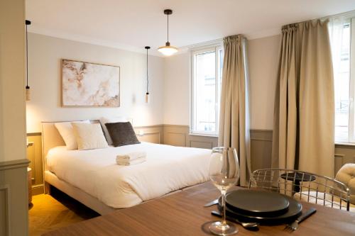 a bedroom with a bed and a table with a wine glass at Studio haut de gamme - Hypercentre - Lit Queen in Caen