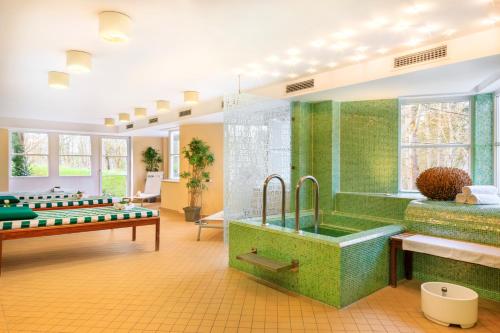 a green bathroom with a tub and a shower at relexa hotel Schatten Stuttgart in Stuttgart