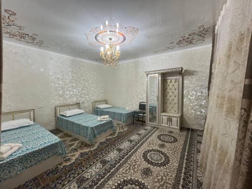 a room with two beds and a chandelier at Musobek Guest House in Khiva