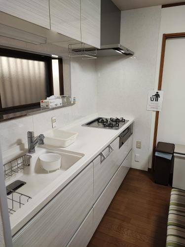 a white kitchen with a sink and a stove at 天王寺まで電車にて 約10分 福宿八尾 in Yaochō