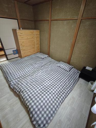 a bed in a room with a checkered blanket at 天王寺まで電車にて 約10分 福宿八尾 in Yaochō