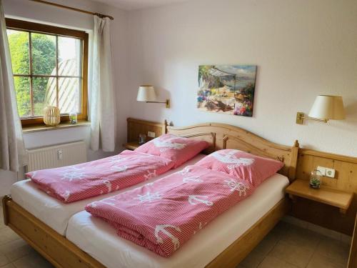 a bedroom with a bed with pink sheets and a window at Landhaus am See App. 2 in Pönitz am See