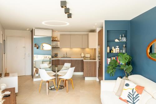 a living room and kitchen with a table and chairs at Appartement luxe vue mer et collines avec piscine in Mandelieu-La Napoule