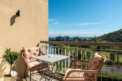 a patio with two chairs and a table on a balcony at Appartement luxe vue mer et collines avec piscine in Mandelieu-La Napoule