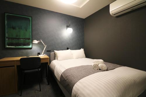 a hotel room with two beds and a desk and a bed sidx sidx sidx sidx at TAKETO STAY PREMIERE SAPPORO EKi in Sapporo