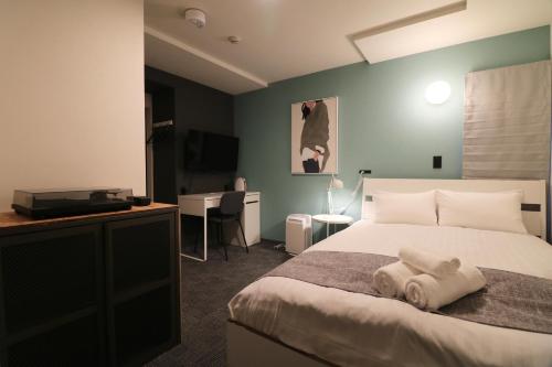 a bedroom with a bed with a towel on it at TAKETO STAY PREMIERE SAPPORO EKi in Sapporo
