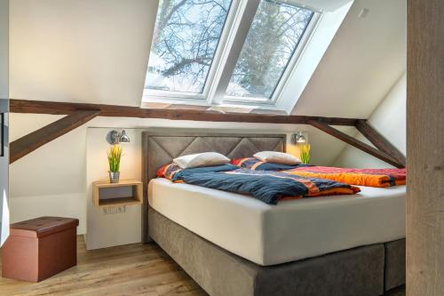 a bedroom with a large bed with two windows at Ahrenshof 7 in Bad Zwischenahn