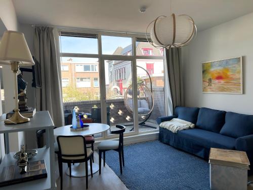 a living room with a blue couch and a table at Strandhuis Scheveningen - Studio Apartments in Scheveningen