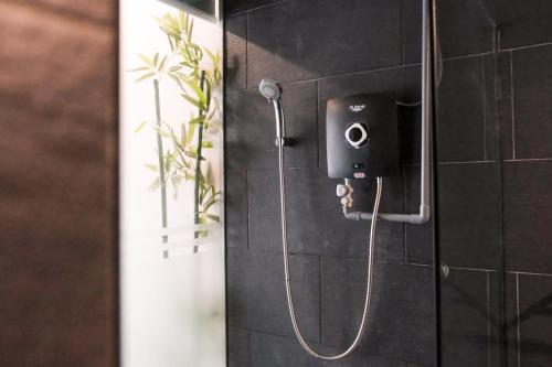 a shower in a black tiled bathroom with a shower at Love Inn Hotel Kuchai Lama in Kuala Lumpur