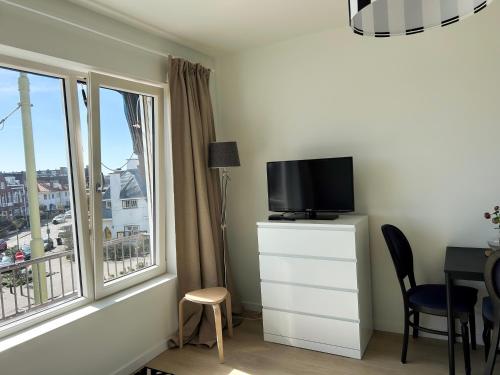 a room with a tv on a dresser with a window at Strandhuis Scheveningen - Studio Apartments in Scheveningen