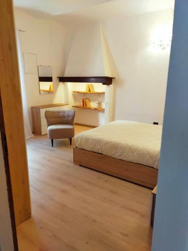 a bedroom with a bed and a chair at La Finestra sul Corso 3 in Arcidosso