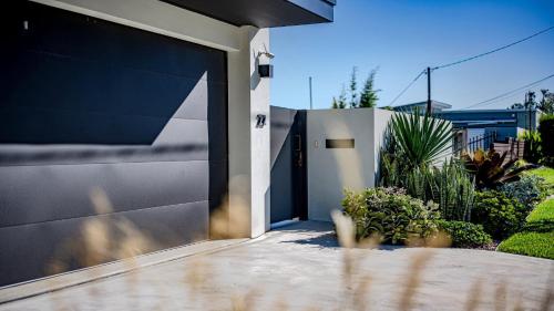 a garage door of a house with plants at 'Sea Mist' by HolidayCo in Hardys Bay