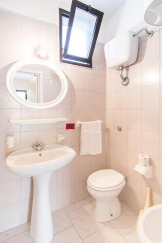 a bathroom with a toilet and a sink and a mirror at Racar Hotel in Frigole