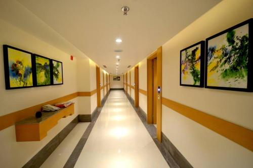 a hallway with a long aisle with paintings on the walls at Pearltree Hotels And Resorts in Purulia