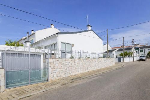 a white house behind a stone wall with a fence at Private Room in Corroios 15 Minutes from the Beach - Quarto Privado em Corroios com Fácil Acesso à Praia e Lisboa in Corroios