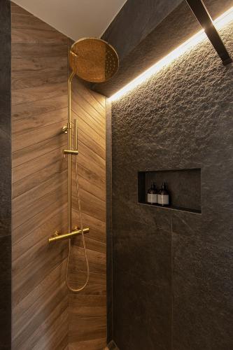 a shower in a bathroom with wooden walls at Allure Chalet, z prywatnym jacuzzi, z widokiem na góry in Dzianisz