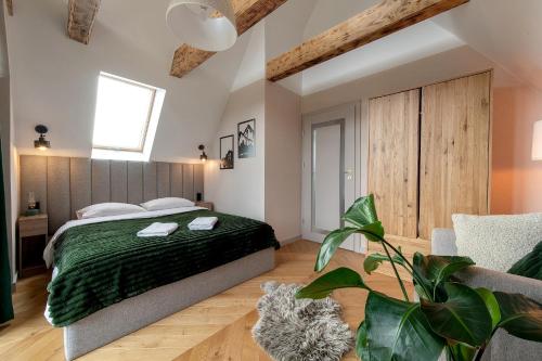 a bedroom with a large bed with a green blanket at Allure Chalet, z prywatnym jacuzzi, z widokiem na góry in Dzianisz