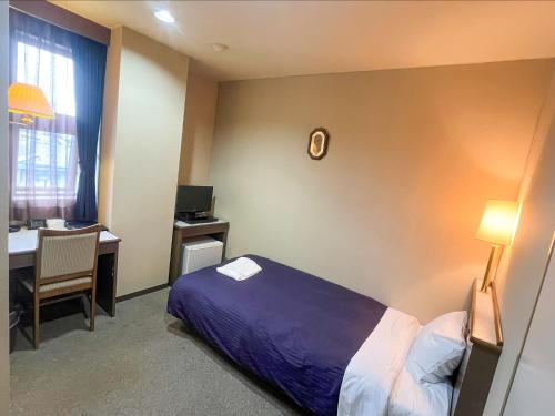 a hotel room with a bed and a desk with a computer at Hotel Livemax Tagajo in Tagajo