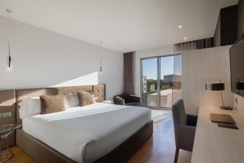 a bedroom with a large white bed and a desk at Hotel SB BCN Events 4* Sup in Castelldefels