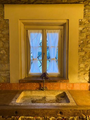 a window with blue curtains in a stone wall at BORGO VILLA VALENTINI in Scandiano