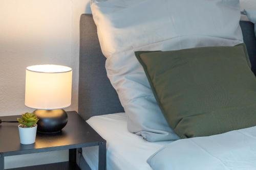 a bed with a table with a lamp and a green pillow at Stilvolles Apartment im Bochumer Stadtkern in Bochum