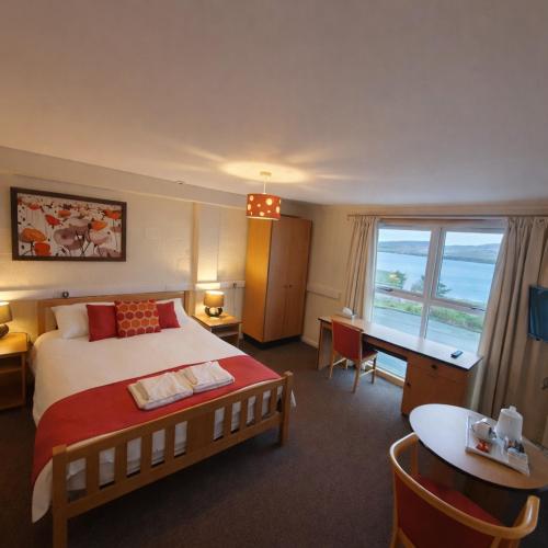 a hotel room with a bed and a desk and a window at The Brae Hotel in Brae