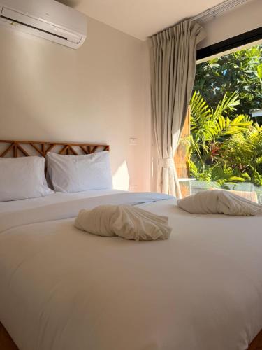 a bedroom with a large white bed with a window at Srithanu Escape 2 in Srithanu