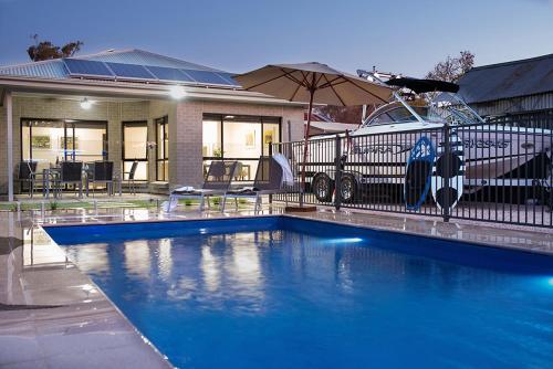 a house with a blue swimming pool in front of a house at Renmark River Villas and Boats & Bedzzz in Renmark