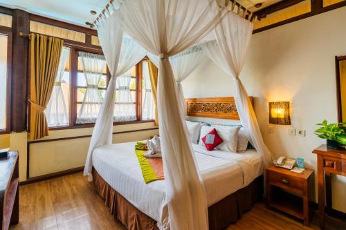 a bedroom with a canopy bed with curtains at Desamuda Village by Pertama Stay in Seminyak