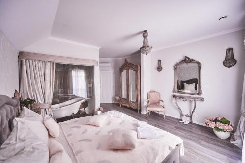 a white bedroom with a tub and a bed and a bath room at Dworek Bukowy Park in Szczecin