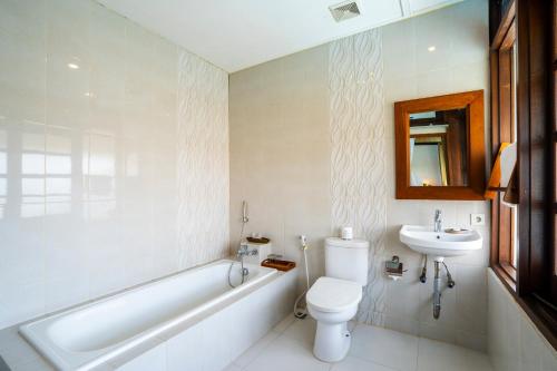 a bathroom with a toilet and a bath tub and a sink at Desamuda Village by Pertama Stay in Seminyak