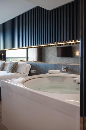 a large bath tub in a room with a bed at Hotel SB BCN Events 4* Sup in Castelldefels
