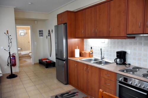 a kitchen with wooden cabinets and a stainless steel refrigerator at Seaside apartment platana kimis evoia in Kymi