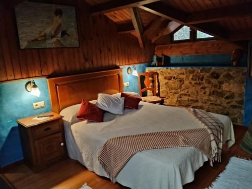 a bedroom with a bed and a stone wall at Río da Cruz in Cariño