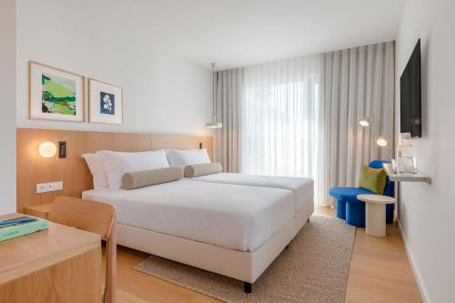 ein Hotelzimmer mit einem weißen Bett und einem Schreibtisch in der Unterkunft Hotel Orquidea in Funchal