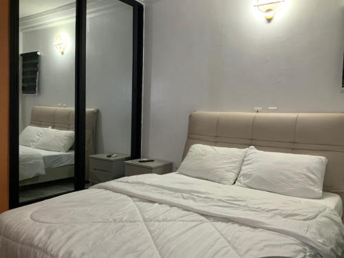 a bedroom with a white bed and a mirror at La MAISON SEONE SILVER in Abidjan