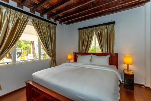 a bedroom with a large bed with two windows at Dara Express Inn by Angkor Green Gardens in Phumĭ Thnál