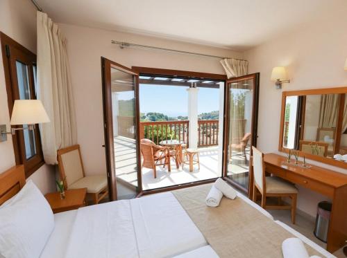 a hotel room with a bed and a desk and a balcony at Cave Luxury Villas Skiathos in Troulos