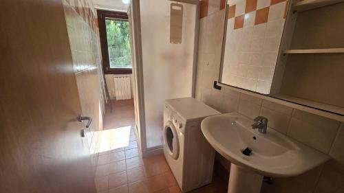 a bathroom with a sink and a washing machine at Functional and equipped apartment in Rosolina in Rosolina Mare