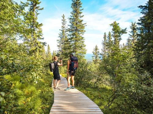 two people walking on a boardwalk in the woods at 12 person holiday home in IDRE in Idre