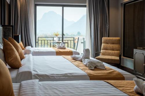 two beds in a hotel room with a large window at Eden De Vangvieng in Vang Vieng
